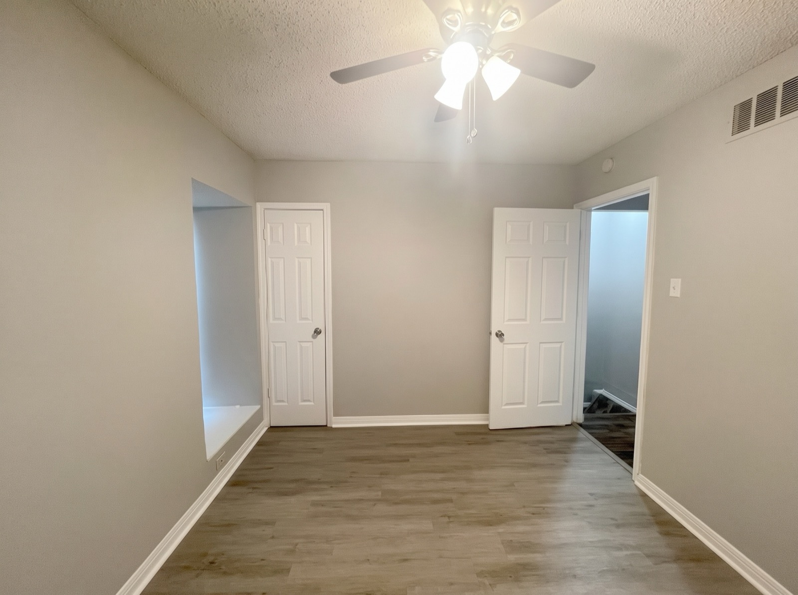 A Hamilton Place living room, empty, with two panelled doors, a recessed niche and plank flooring.