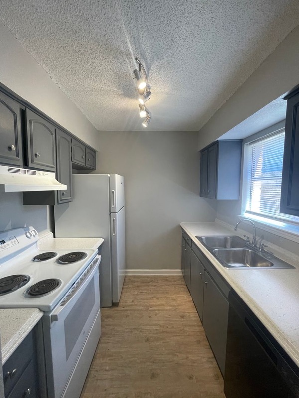 The Contessa kitchen: a white range, a double sink under the window and dark base cabinets.