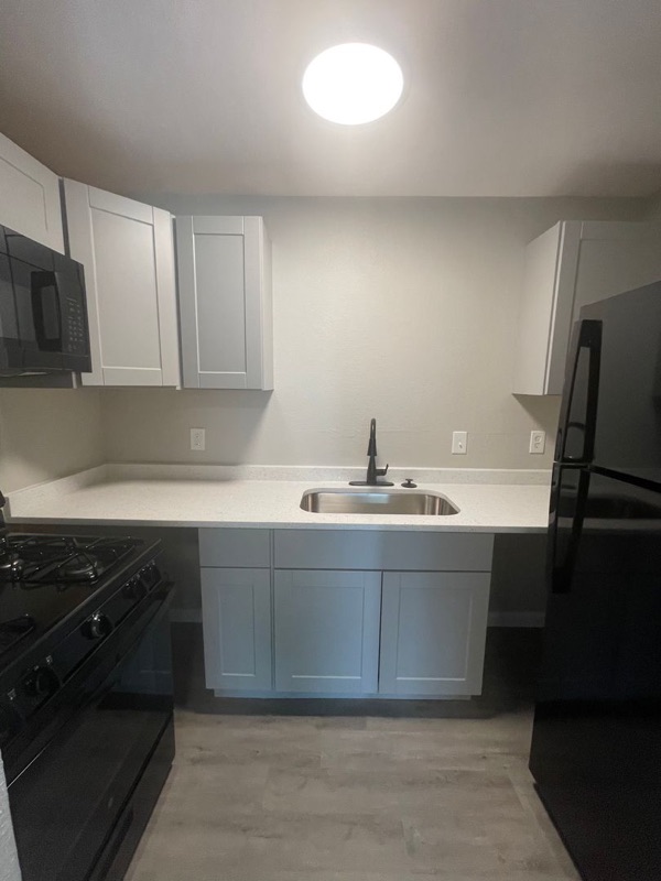The Eleanor kitchen: white upper cabinets, a black range and a sink under the counter run.