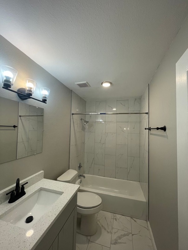 An Eleanor bathroom with a marble-tiled shower, a black-framed mirror and a wall-hung vanity.